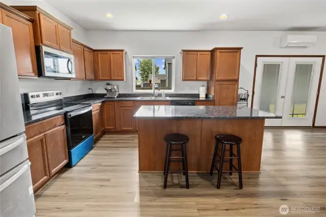Kitchen with granite counters, NEW range and mircrowave and ample cabinets. French doors leading the back yard.