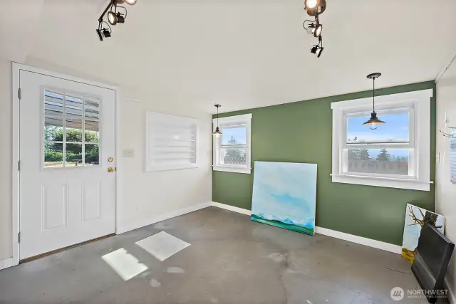 Attached studio space with separate entrance. Complete with accessible outlets, lighting, shelving and a robust exhaust fan previous used as an art studio). Concrete flooring leaves you with many possibilities for use.