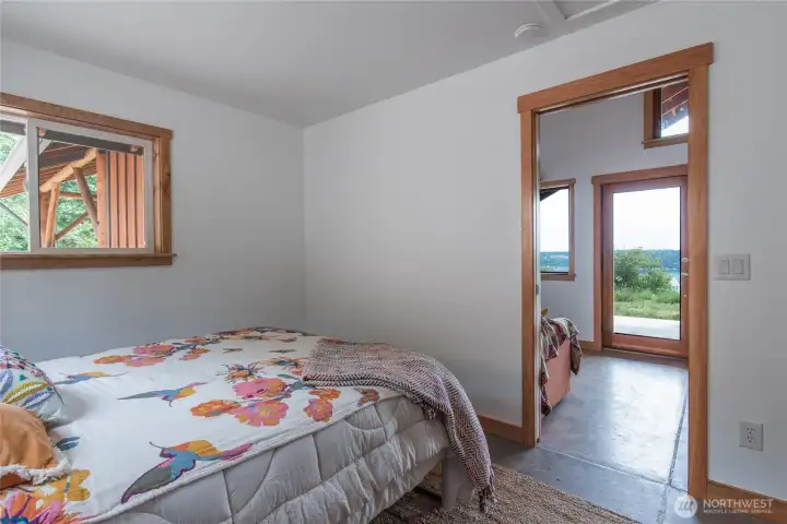 Comfortable bedroom with queen size bed that has a view of the water with the door open. Good morning Hood Canal!