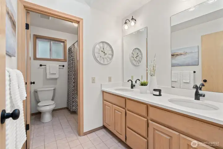 Full hallway bathroom with double vanity, Corian counters, new quartz sinks, skylight and tile floor.