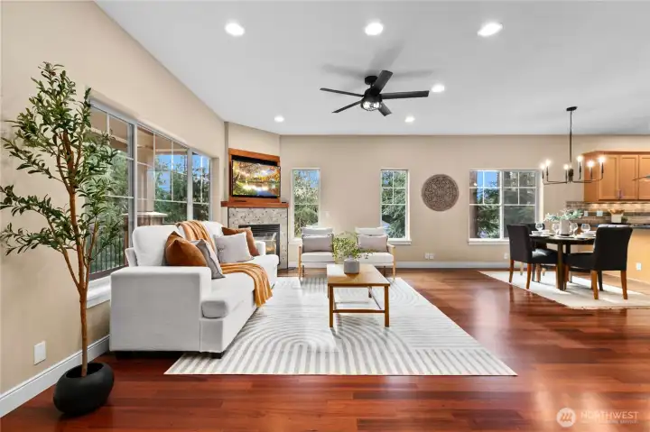 Living area with hardwood floors, large windows, and fireplace creating a central gathering space.