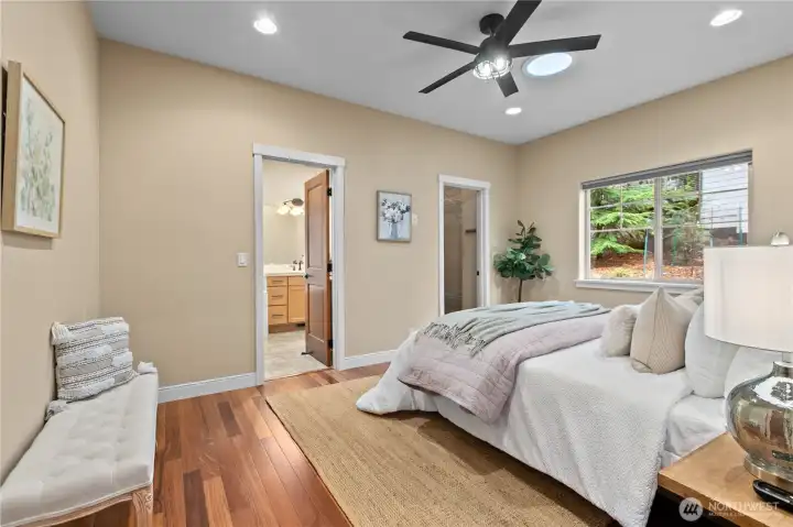 Primary bedroom with hardwood flooring and direct access to ensuite bath.