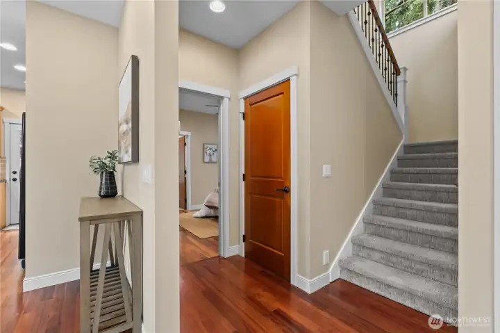Main-level hallway with hardwood flooring, staircase access, and interior room connections.