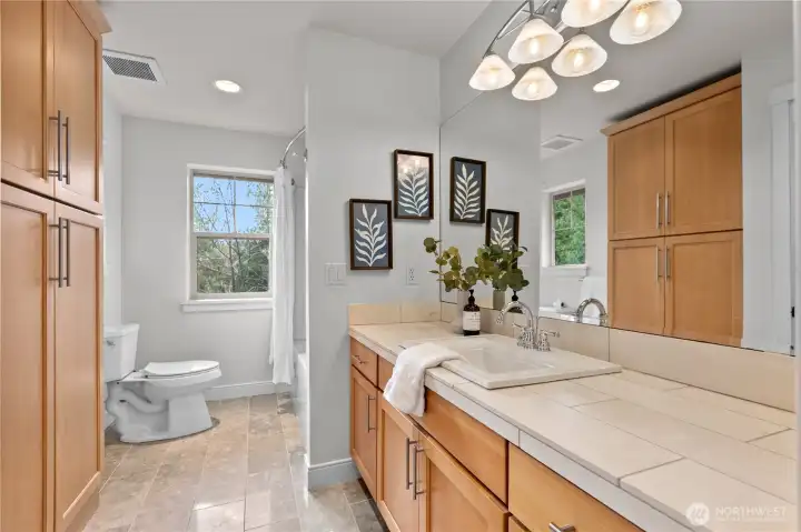 Full bathroom upstairs with large vanity, extra cabinents, and adjacent tub/shower combination