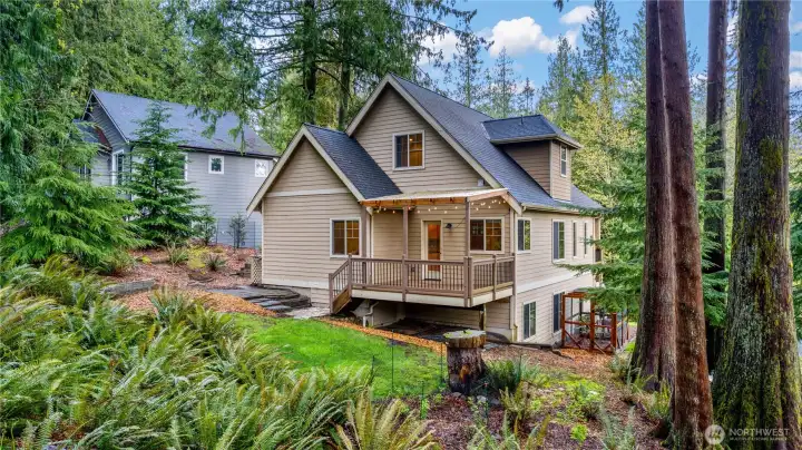 Exterior perspective showing home set among mature trees with natural surroundings
