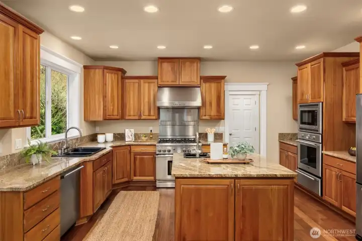 Fantastic cook's kitchen features Thermador range, hood, wall oven and warming drawer. Note the prep sink on the large island. Just through the white door in the right of the photos is a laundry room and walk-in pantry.