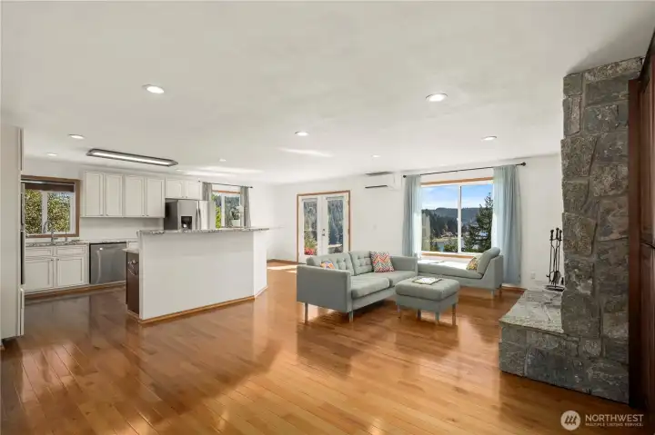 Sun-filled open living with warm hardwood floors, a cozy stone fireplace, and an easy flow to the kitchen—plus picture windows that frame the Hood Canal view.