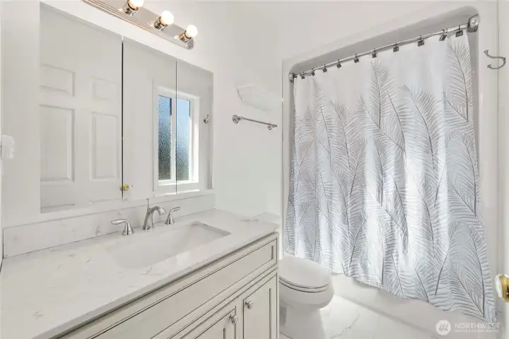 Bright primary bath finished with quartz counters and matching quartz flooring—clean, modern, and easy to maintain.