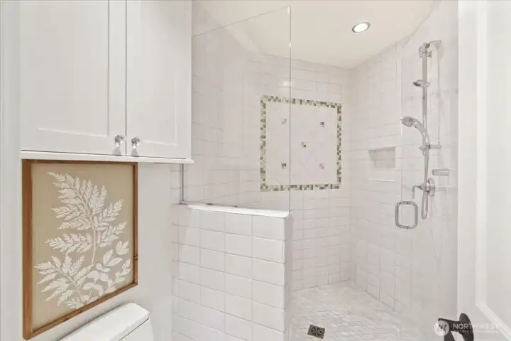 This beautifully updated bathroom features custom floor to ceiling ceramic tile and heated floors.