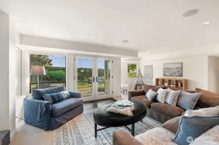 The lower-level rec room opens through French doors directly to the lawn, creating an easy flow from indoor play to outdoor fun.