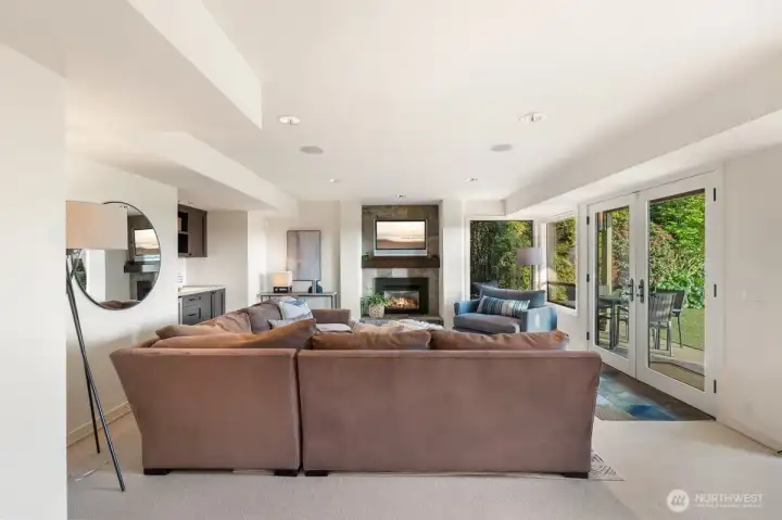 The lower-level rec room features a fireplace, beverage refrigerator, and minibar area, with abundant south-facing light throughout the day.