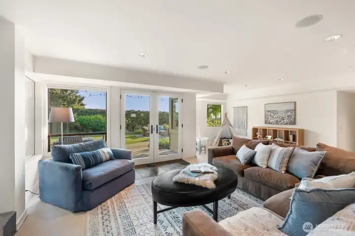 The lower-level rec room opens through French doors directly to the lawn, creating an easy flow from indoor play to outdoor fun.