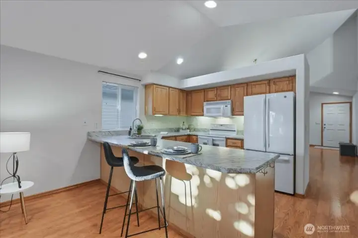 Kitchen with peninsula and eat bar, vaulted ceilings, laminate floor