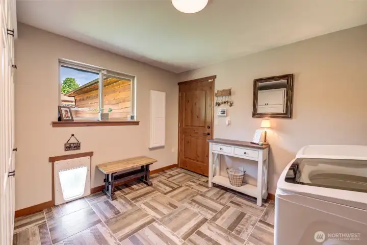 Well-appointed laundry room features durable finishes, exterior access, and ample storage and workspace.