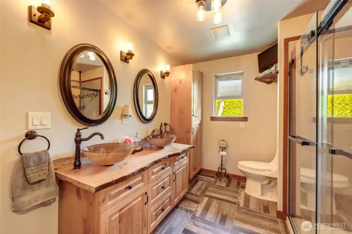 Dual vessel sinks, custom cabinetry, and a glass shower create a luxurious primary suite experience.