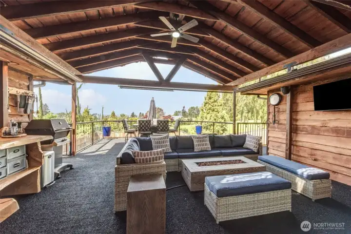 Exceptional covered outdoor living area featuring a built-in barbecue, lounge space, and sweeping territorial views.