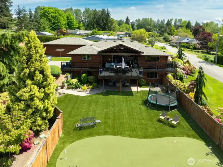 Expansive backyard retreat featuring a private putting green, generous lawn space, and room for recreation, play equipment, and outdoor gatherings.