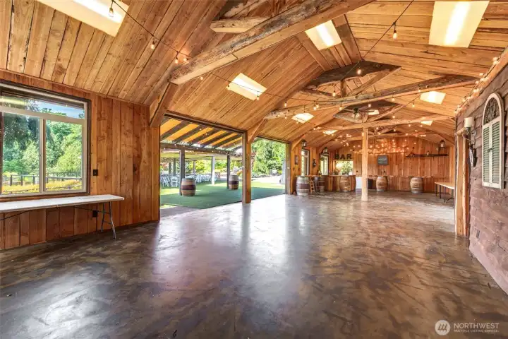 A stunning timber-frame event barn provides versatile indoor event space for dining, dancing, receptions, corporate gatherings, and private celebrations, all centered around a built-in bar and open-concept layout.