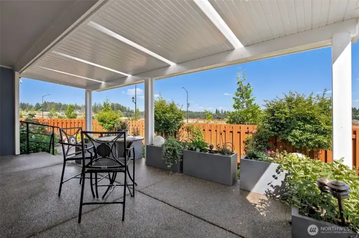 This covered patio was designed to extend your living space well beyond the walls of the home. The attractive aggregate concrete surface provides a durable, upscale finish underfoot, while the deep covered design offers plenty of room for outdoor dining, grilling, relaxing or gathering with friends. A handsome white plank ceiling creates a bright and airy feel overhead, and thoughtfully placed skylight panels allow additional natural light to filter into the space without sacrificing protection from the elements. Whether you're enjoying a quiet morning coffee or hosting a summer dinner party, this inviting outdoor retreat lets you enjoy the breathtaking Mt. Rainier view and fresh air in comfort throughout the year.