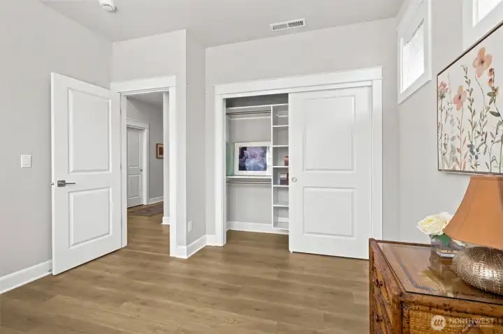 A closer look reveals why this room feels so polished. The built-in closet organization helps keep everything tidy and accessible, while the handsome wood-wrapped window brings a custom-home touch that adds warmth and character to the space. The soft whisper-gray color palette leans warm rather than cool, creating a cozy atmosphere that works beautifully with virtually any décor style and complements the flooring perfectly. Just across the hallway, the nearby full bathroom enhances the room's appeal as a guest retreat, office or hobby space. Combined with the privacy-focused layout that keeps bedrooms separated from one another, it's another example of how thoughtfully this home was designed for comfortable everyday living.