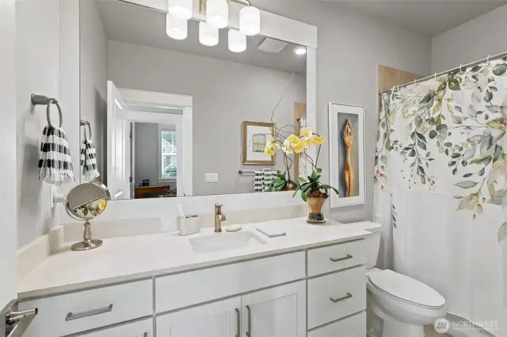 Conveniently located just off the foyer and directly across from the front guest bedroom, this full bathroom creates a wonderful private guest wing arrangement. The extra-long vanity provides generous counter space, making it easy for visitors to spread out without feeling cramped, while the quartz countertop and undermount sink deliver the timeless finishes buyers love. A full tub and shower surround offers flexibility for guests, grandkids or the occasional relaxing soak. Clean lines, classic materials and a neutral color palette ensure this space will remain stylish for years to come.