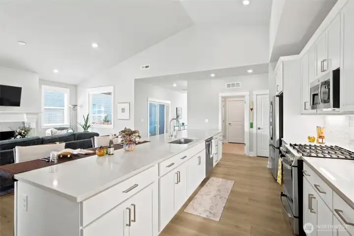 The kitchen flows effortlessly into the living room, allowing conversations to continue whether you're preparing dinner, entertaining guests or simply enjoying a quiet evening at home. In the distance, you can see the sliding glass door leading to the charming covered side patio, creating yet another indoor-outdoor living opportunity. Comfort is handled efficiently by the home's heat pump system, providing both heating and cooling throughout the seasons. Another thoughtful feature buyers often overlook is the placement of the forced-air registers in the ceiling rather than the floor, giving you much more freedom when arranging furniture without worrying about blocking vents with a sofa, bed or favorite reading chair.