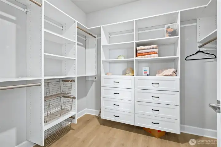 The primary suite closet has a California Closet organization system with built-in drawers, shelves, wire baskets and handsome wood hanging rods creating a customized storage solution that maximizes every inch of space. There's room for shoes, handbags, folded clothing, accessories and all the things that somehow multiply over the years. Upper shelving provides additional storage for seasonal décor, luggage and those items you want nearby but not necessarily on display. Organized, efficient and beautifully designed, this closet feels like a boutique dressing space.