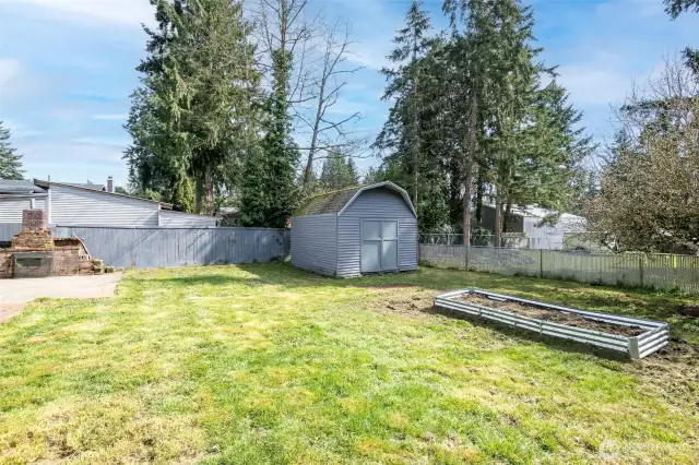 Rear and side yard with large storage shed and raised garden