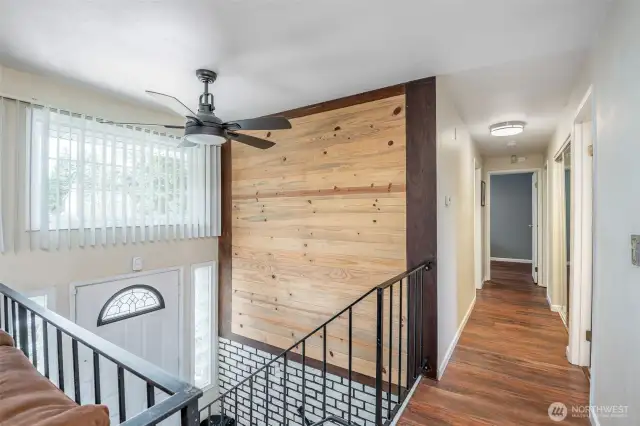 Entry with natural wood wall and hall to bedrooms and bathroom