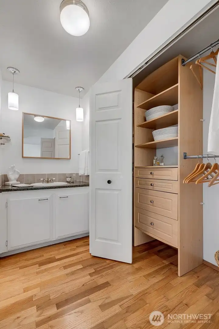 The primary bedroom with a built-in closet system and an additional separate vanity from the main bath. Original oak hardwood floors.