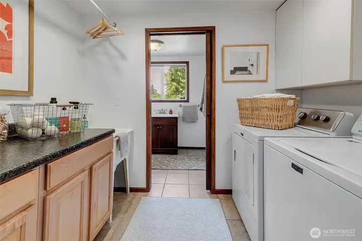 Spacious laundry room with folding table and extra storage cabinets on both sides, plus a deep tub utility sink and a convenient hanging bar for drying delicates.  The ¾ bath is adjacent.