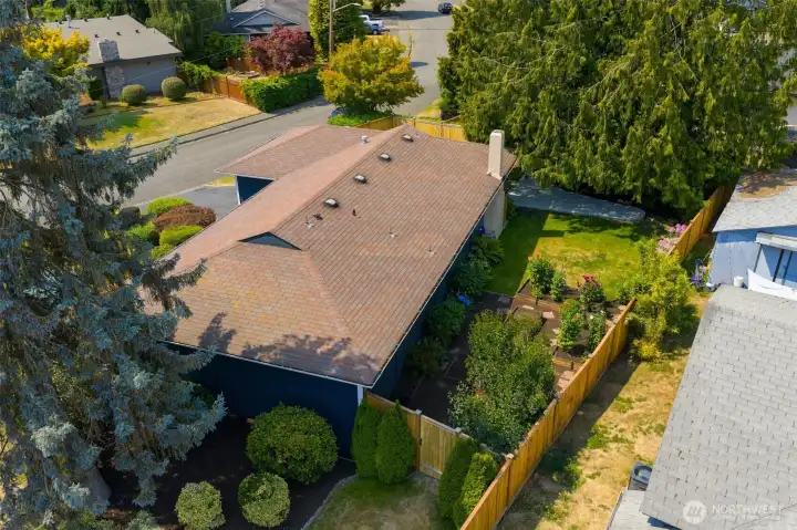 An aerial image of the back yard and the east side yard. There is also a grassy area and patio on the west side.