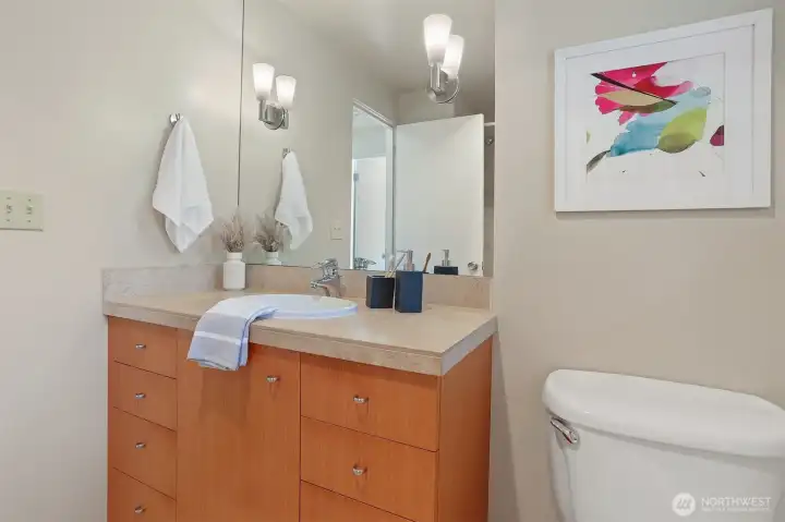 A jewel-box full bath reimagined with quartz counters, white oak cabinetry, and sculptural lighting.