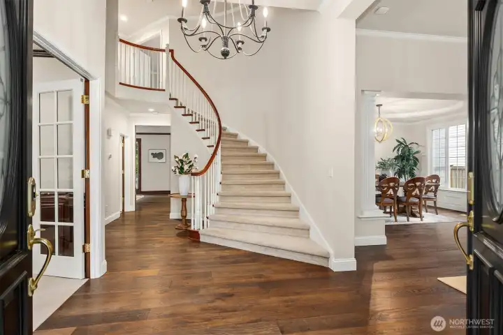 A dramatic, grand curving staircase greets you in the light-filled entry, setting the tone for the home’s elegant interior.