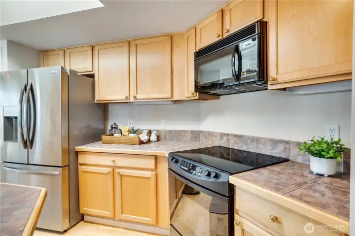 Freshly painted and thoughtfully designed, the kitchen features abundant cabinetry and a newer stainless steel fridge.