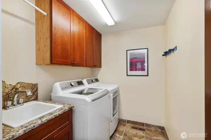 Main level laundry room with deep sink and granite backsplash.
