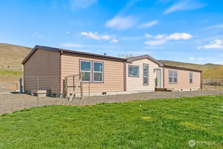 Additional exterior angle highlights the home’s footprint and surrounding land, showcasing the privacy and flexibility that acreage living provides.