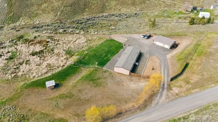 Bird’s-eye view highlighting the overall layout—home, detached shop, driveway access, and defined outdoor spaces across nearly 4 acres.