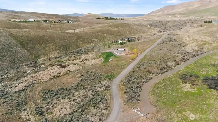 Wide aerial showing approach from the road, giving a clear sense of privacy, spacing from neighbors, and easy access to the property.