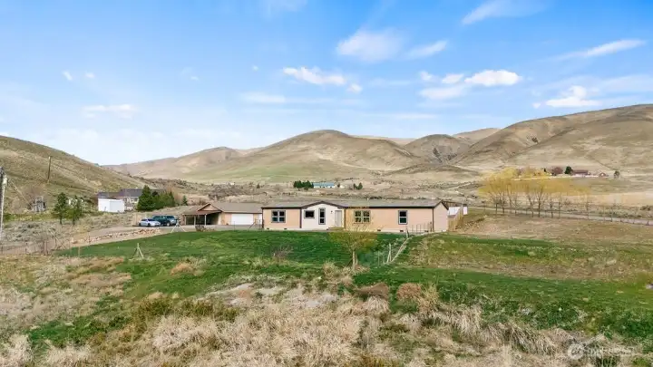 Lower elevation view highlighting the blend of open pasture, green lawn space, and surrounding valley terrain.