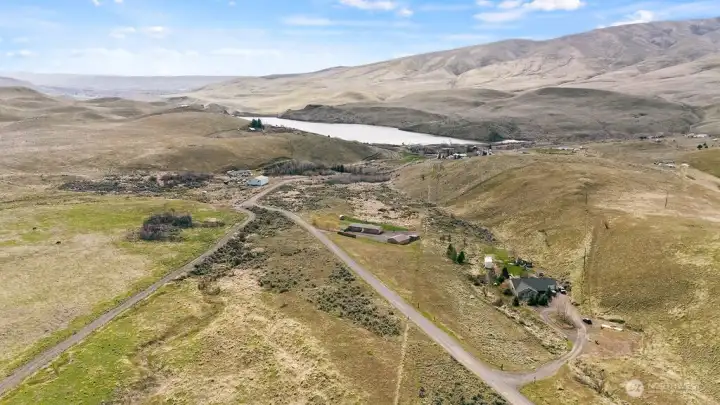 Expansive aerial showing the broader Wenas Valley landscape, including distant water views and the natural beauty that surrounds the property.