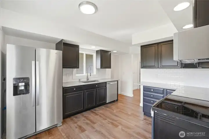 Kitchen with black cabinetry, light quartz countertops, white subway tile, and a stainless Whirlpool fridge, dishwasher, and range. Kitchen with black cabinetry, light quartz countertops, white subway tile, and a stainless Whirlpool fridge, dishwasher, and range.