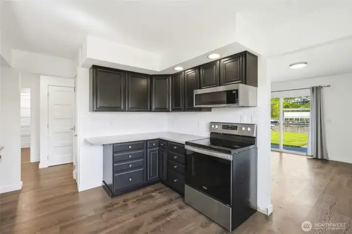 Range and microwave nook beside a sliding glass door leading straight to the backyard. Range and microwave nook beside a sliding glass door leading straight to the backyard.