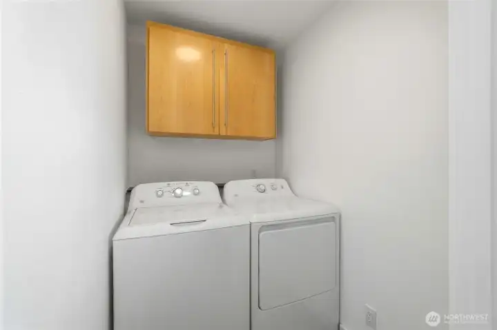 Laundry room with washer and dryer beneath a wall-mounted storage cabinet. Laundry room with washer and dryer beneath a wall-mounted storage cabinet.