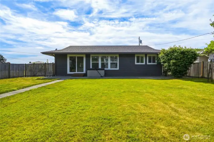 Rear of the home with a covered hot tub on the patio and sliding glass door access to the living room. Rear of the home with a covered hot tub on the patio and sliding glass door access to the living room.