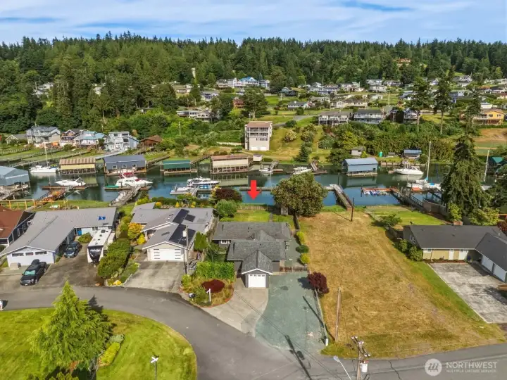 Aerial view showing the home's position along the canal, with the marina and forested hillside beyond. Aerial view showing the home's position along the canal, with the marina and forested hillside beyond.