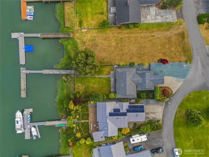 Straight-down aerial view of the property, showing the roofline, yard, and dock access along the canal. Straight-down aerial view of the property, showing the roofline, yard, and dock access along the canal.