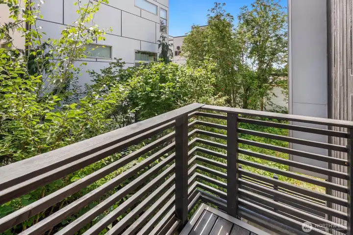 A private balcony extends from the second bedroom, offering a peaceful retreat among the trees.