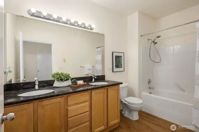 The primary bathroom features slab granite counter, dual sinks and new luxury vinyl flooring.