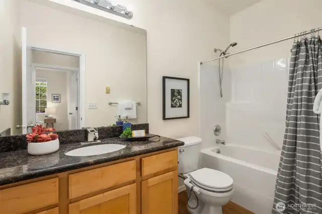 Full bath with granite counters and luxury vinyl flooring.